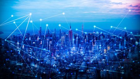A cityscape with a blue filter over it has a series of lines and dots overlaid on top.